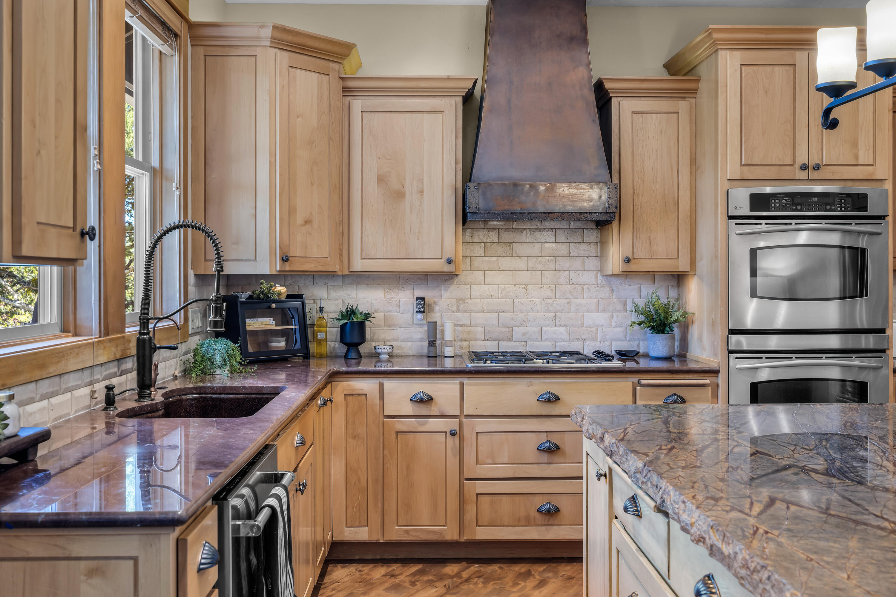 64145 Hunnell Road Bend, OR 97703 - Photo 15 of 65 Warm cabinetry, stone surfaces and a statement hood define the kitchen?s cooking area, with generous prep space and an easy connection to the surrounding dining and living spaces.