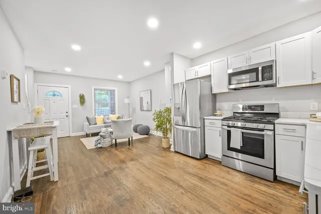 a living room with stainless steel appliances furniture a fireplace a flat screen tv and a window