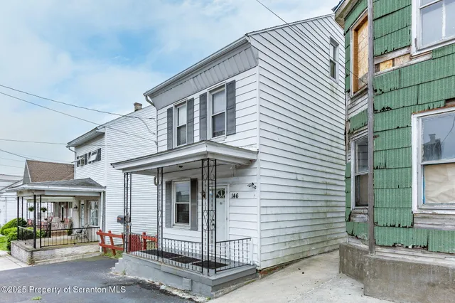 a view of a white house with large windows and potted plants