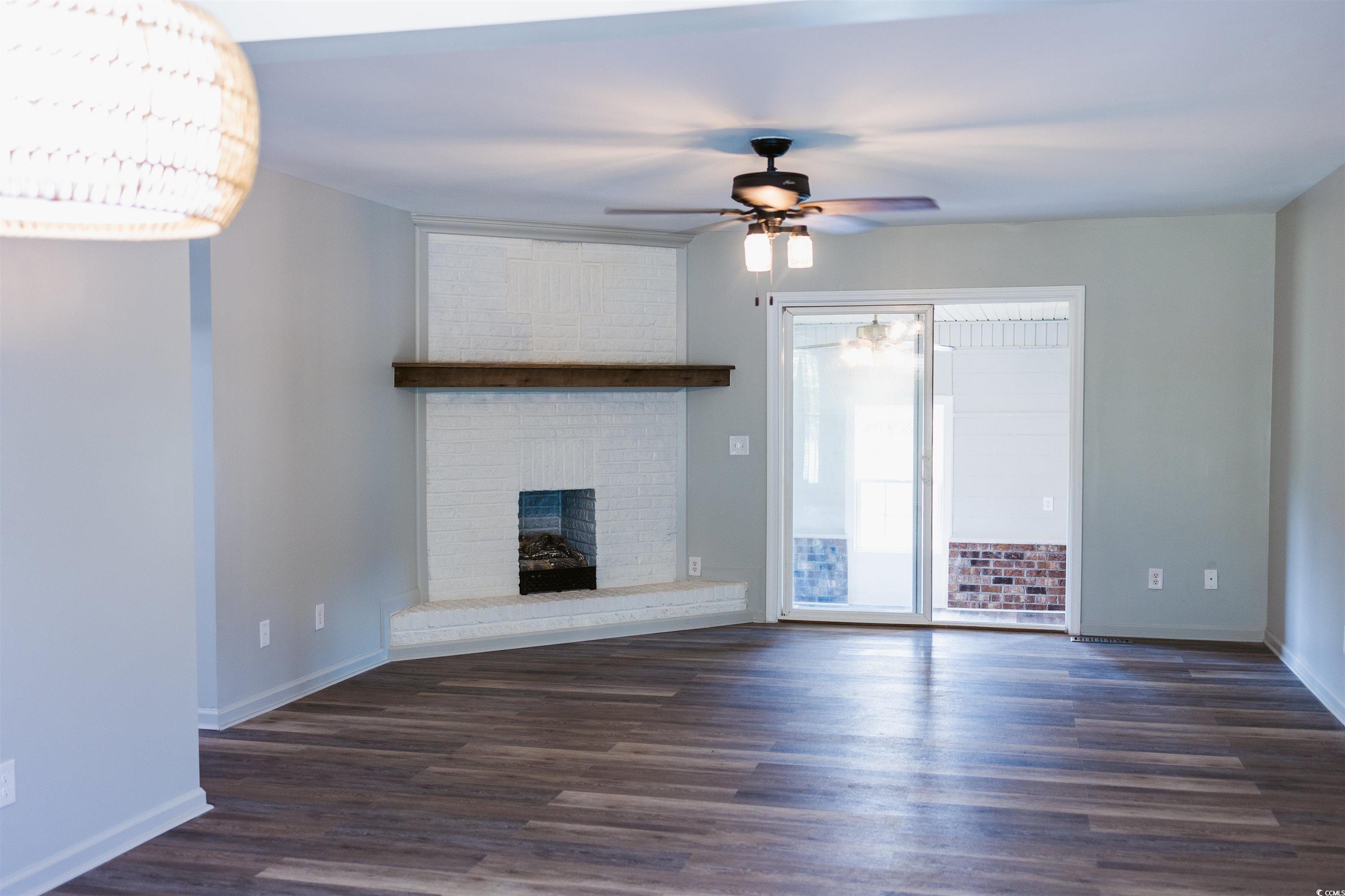 2851 Highway 984 Galivants Ferry, SC 29544 - Photo 15 of 23 Unfurnished living room featuring dark wood-style flooring, a fireplace, and a ceiling fan