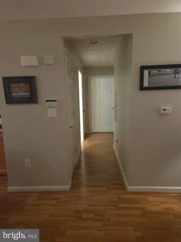 a view of a hallway with wooden floor and a bathroom