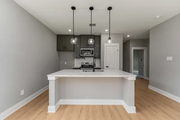 a view of a kitchen with kitchen island a sink and wooden floor