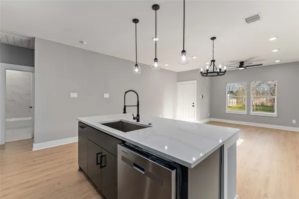a kitchen with stainless steel appliances granite countertop a sink a oven and a wooden floor