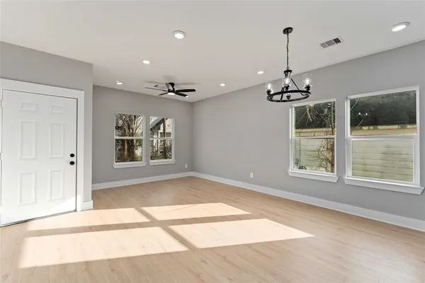 a view of an empty room with a window and wooden floor