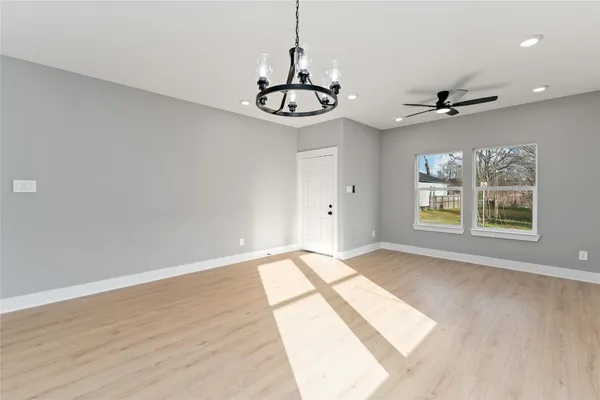 an empty room with wooden floor fan and windows