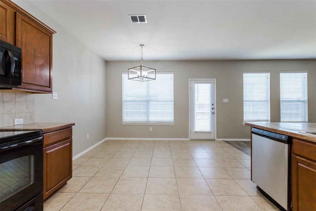 203 Arabian Road Waxahachie, TX 75165 - Photo 11 of 24 Open-concept kitchen and dining area featuring tile flooring, warm wood cabinetry, and a contemporary geometric chandelier