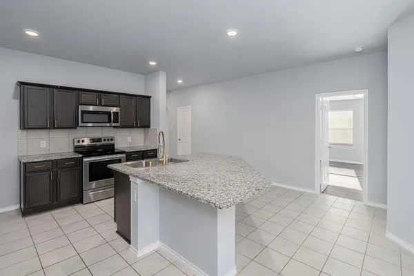 a kitchen with granite countertop a sink and white cabinets