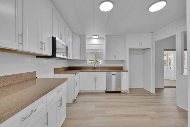 a kitchen with granite countertop white cabinets and stainless steel appliances