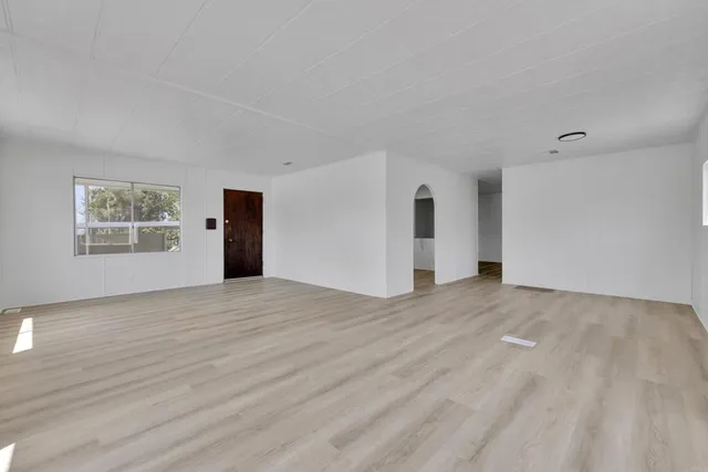 a view of empty room with wooden floor and window