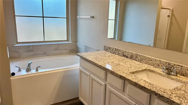 a bathroom with a granite countertop sink and a bathtub