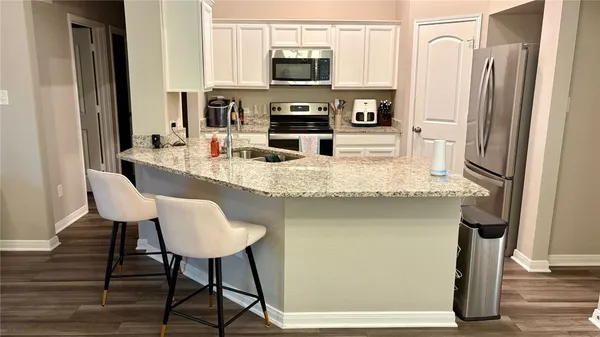 a kitchen with stainless steel appliances granite countertop a sink and a refrigerator