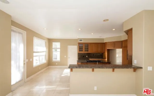 a view of kitchen with stainless steel appliances kitchen island granite countertop a refrigerator and a sink