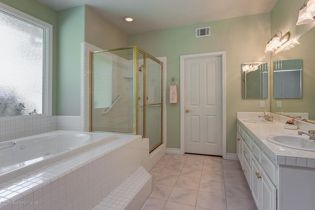 a spacious bathroom with a tub sink and mirror