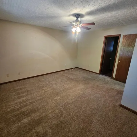 an empty room with a chandelier fan and windows