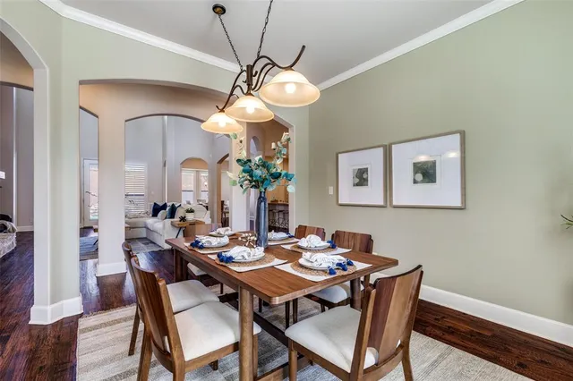 a dining room with wooden floor a chandelier fan a wooden table and chairs