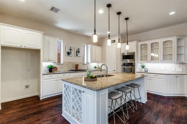 a kitchen with a sink a center island cabinets and stainless steel appliances