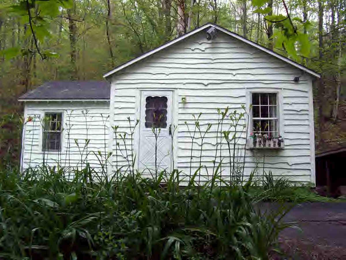 a small white house with a white roof and table and chairs next to window