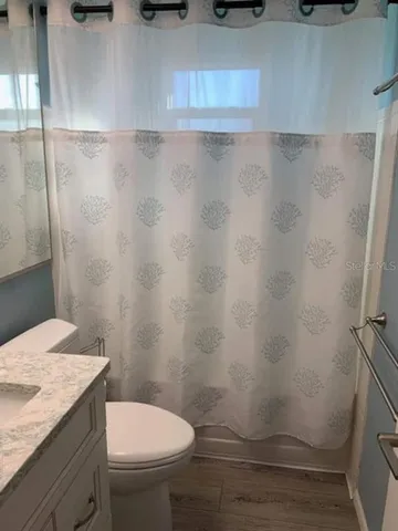 a bathroom with a granite countertop sink and a toilet