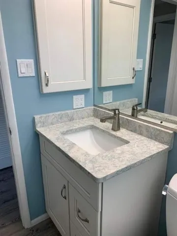 a bathroom with a granite countertop sink and a mirror