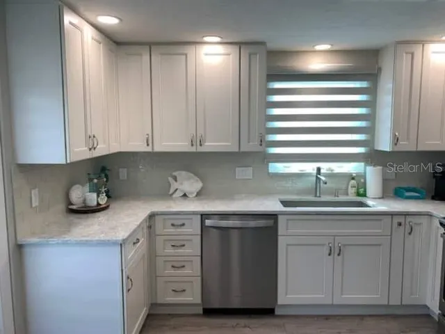 a kitchen with cabinets appliances a sink and a window