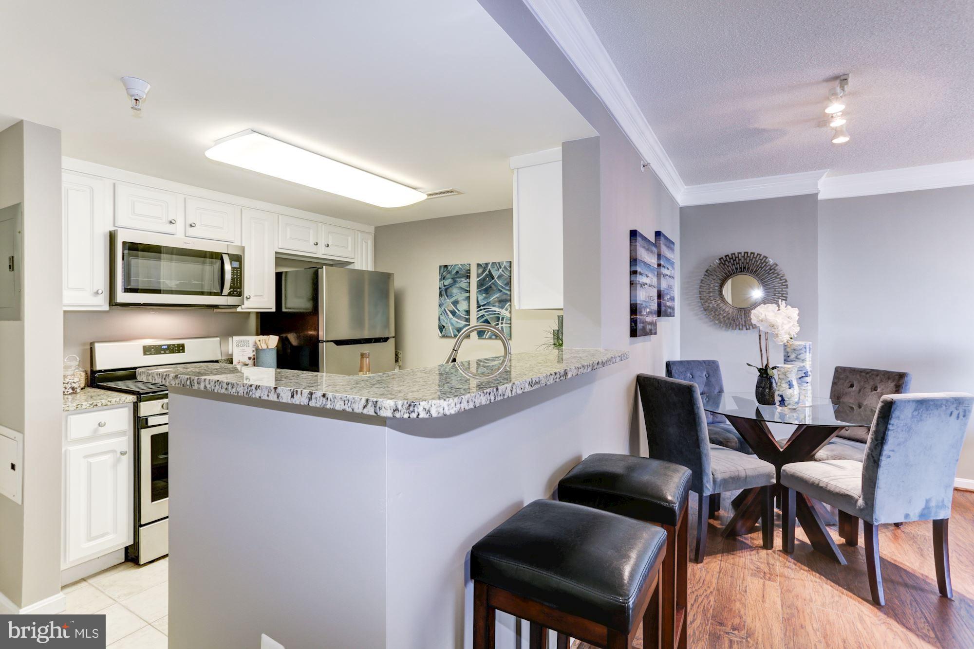 11710 Old Georgetown Road, Unit 1127 North Bethesda, MD 20852 - Photo 2 of 30 a kitchen with stainless steel appliances granite countertop a stove top oven a sink dishwasher a dining table and chairs with wooden floor