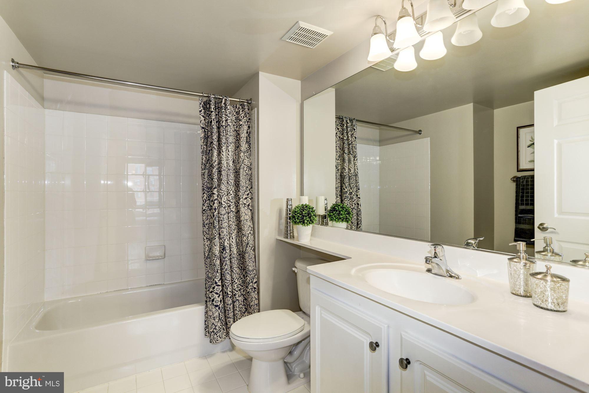 11710 Old Georgetown Road, Unit 1127 North Bethesda, MD 20852 - Photo 16 of 30 a bathroom with a sink a toilet a mirror a bathtub and shower