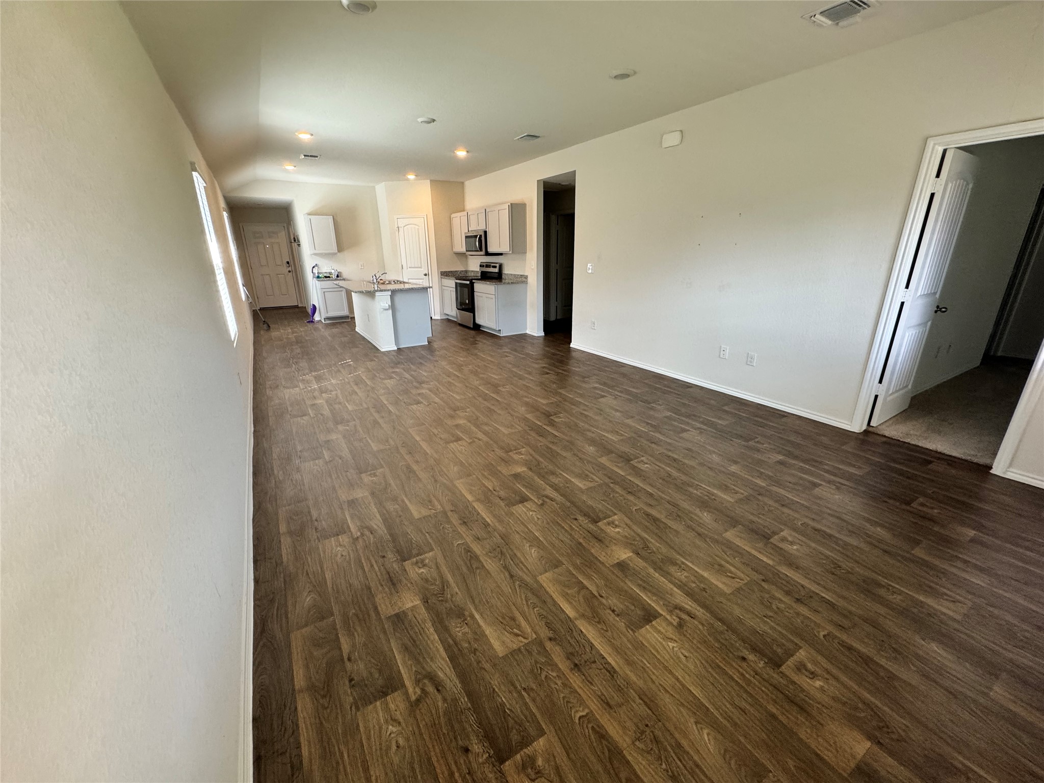 11820 Rush Lane Elgin, TX 78621 - Photo 12 of 31 An open-concept living space boasts wood-look flooring and a functional kitchen island.