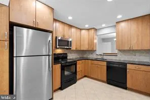 a kitchen with stainless steel appliances granite countertop a refrigerator a stove a sink and a microwave