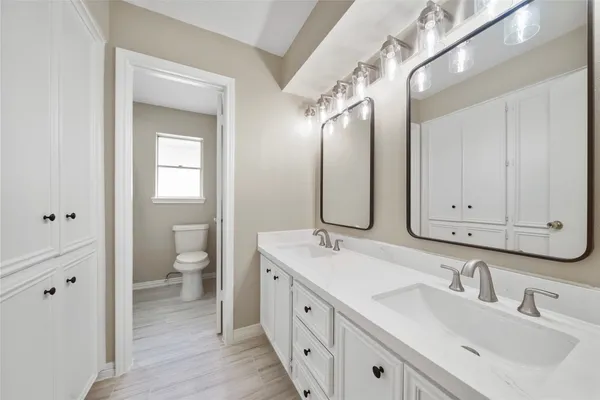 a spacious bathroom with a double vanity sink a mirror and a toilet