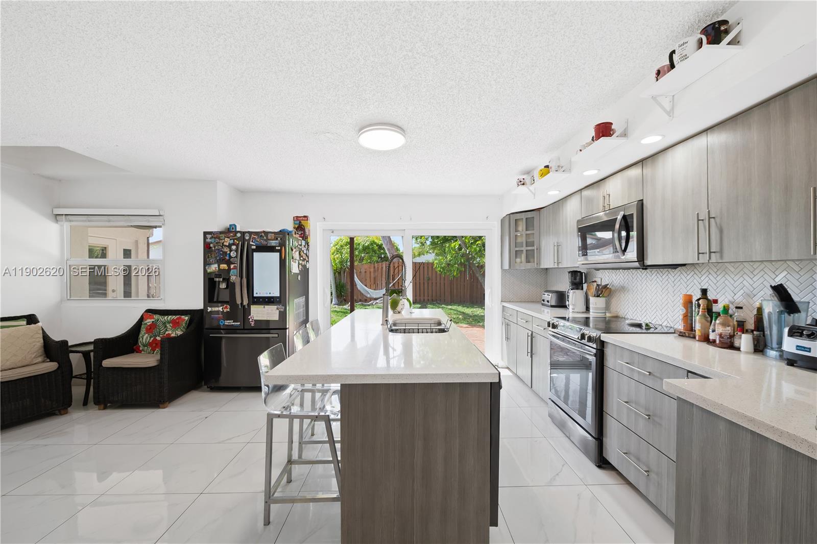 10610 Southwest 128th Avenue Miami, FL 33186 - Photo 29 of 46 a kitchen with counter top space cabinets dining table and stainless steel appliances