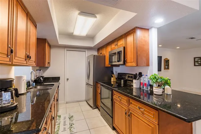 a kitchen with stainless steel appliances a sink dishwasher a refrigerator a stove top oven and wooden floor