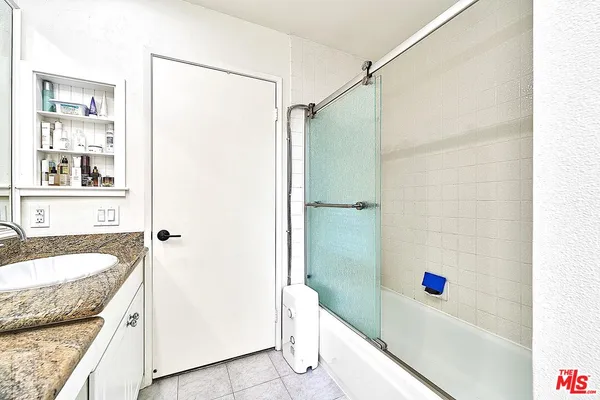 a bathroom with a granite countertop sink a vanity and shower
