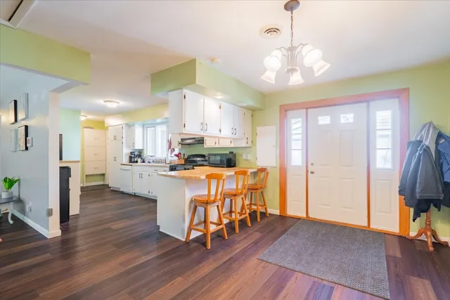 a open kitchen with stainless steel appliances granite countertop a refrigerator a stove a sink dishwasher and a dining table with wooden floor