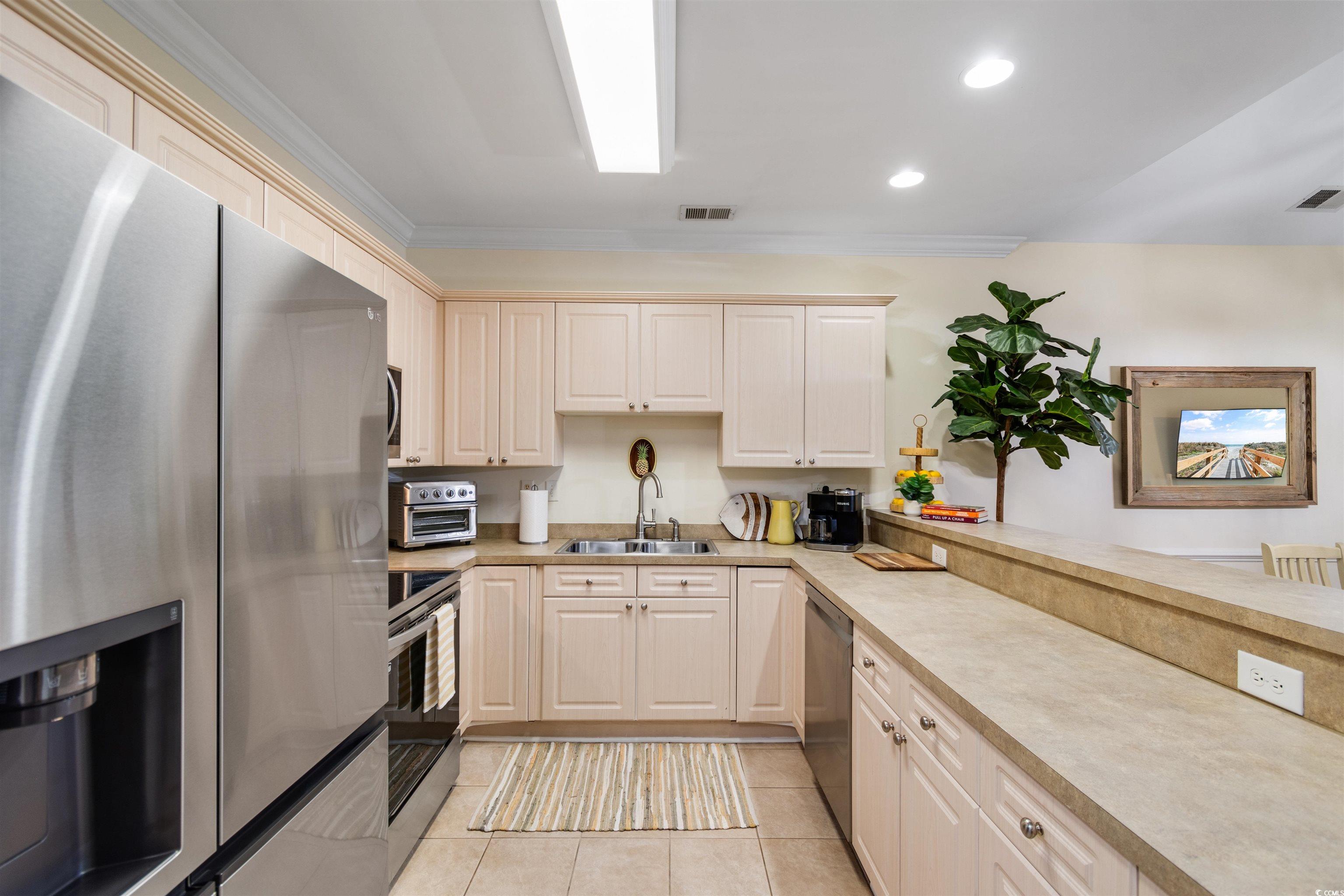 4843 Luster Leaf Circle, Unit 402 Myrtle Beach, SC 29577 - Photo 3 of 33 Kitchen featuring stainless steel appliances, light countertops, light tile patterned floors, recessed lighting, and ornamental molding