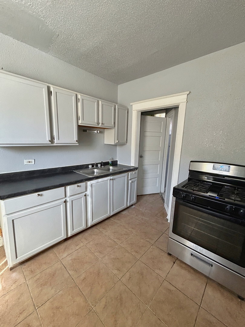 11833 South Perry Avenue Chicago, IL 60628 - Photo 3 of 8 a kitchen with granite countertop a stove and a cabinets