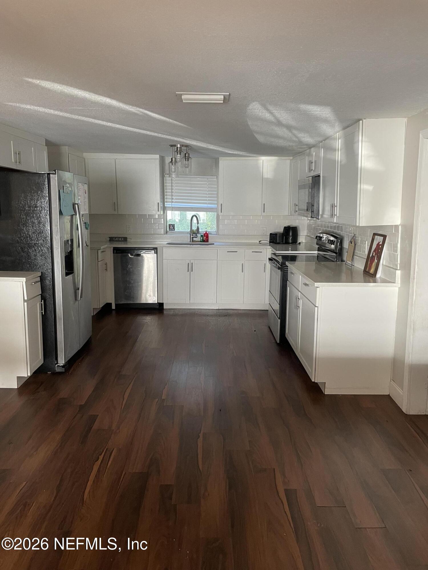 5884 Retha Road Jacksonville, FL 32254 - Photo 4 of 16 a kitchen with stainless steel appliances wooden floors and white counter top
