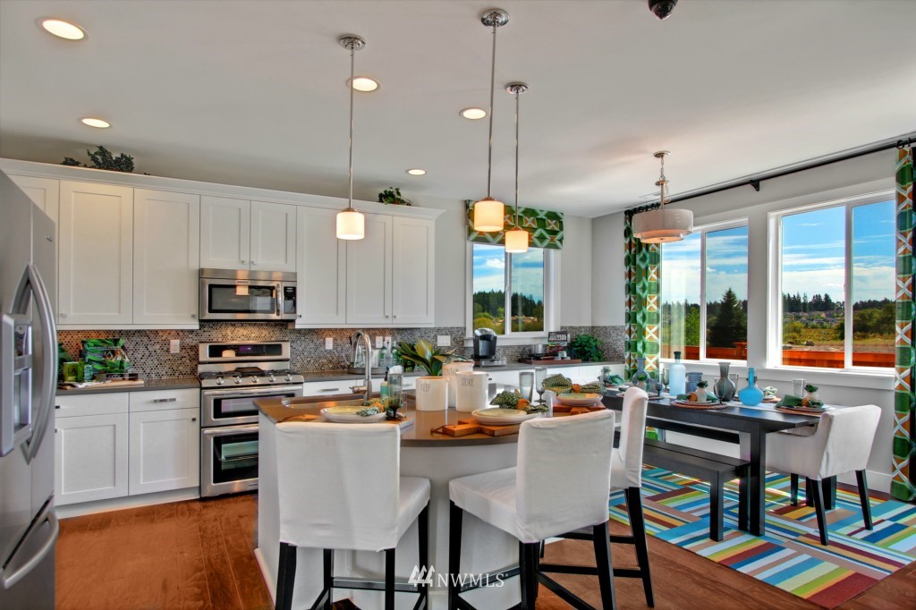 3532 178th Street Southeast, Unit 1002 Bothell, WA 98012 - Photo 4 of 25 a kitchen with stainless steel appliances granite countertop a stove top oven a refrigerator a sink and a dining table with chairs