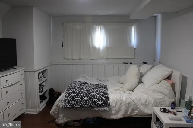 a bedroom with a bed and flat tv screen on the dresser