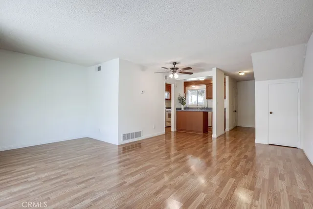 a view of a big room with wooden floor and a kitchen