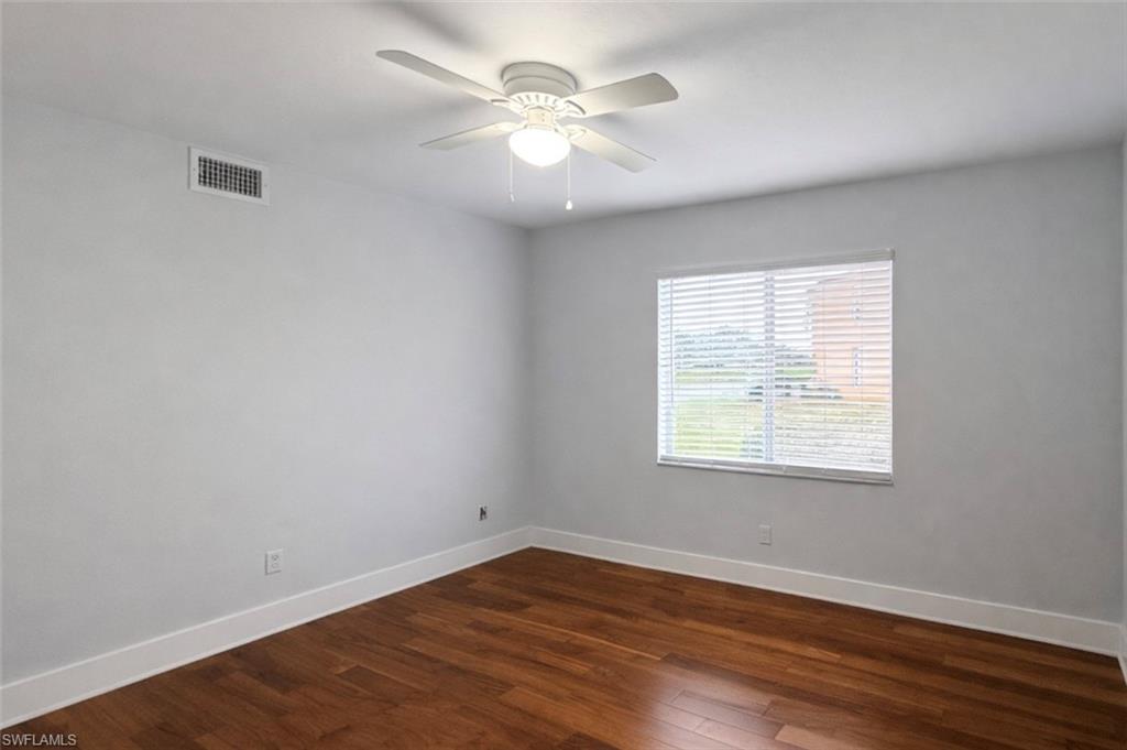 534 Augusta Boulevard, Unit E104 Naples, FL 34113 - Photo 19 of 26 an empty room with wooden floor and windows