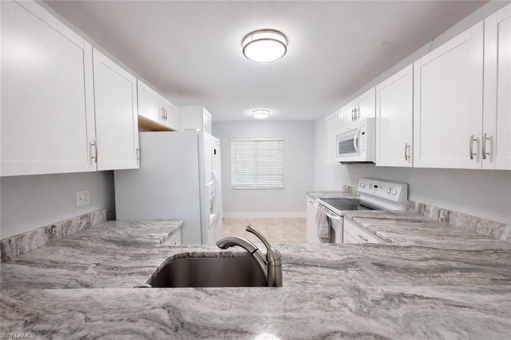 534 Augusta Boulevard, Unit E104 Naples, FL 34113 - Photo 2 of 26 a kitchen with granite countertop a sink a stove and cabinets