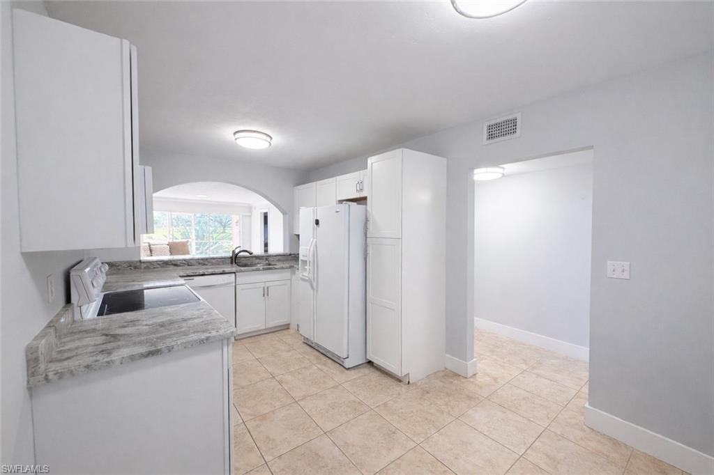 534 Augusta Boulevard, Unit E104 Naples, FL 34113 - Photo 7 of 26 a kitchen with white cabinets and refrigerator