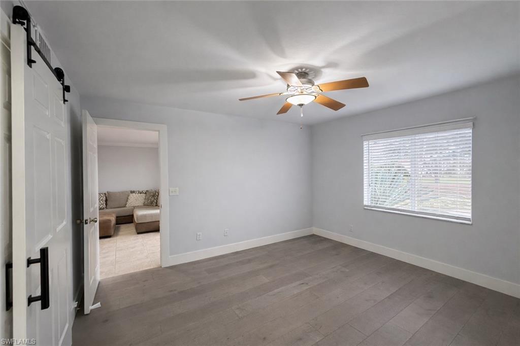 534 Augusta Boulevard, Unit E104 Naples, FL 34113 - Photo 8 of 26 wooden floor in an empty room with a window