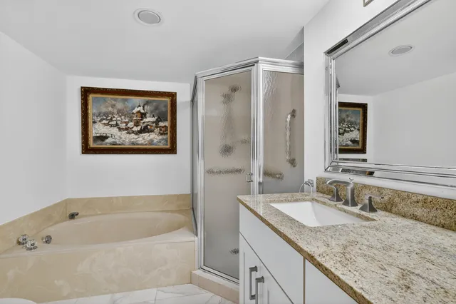 a bathroom with a granite countertop tub sink and mirror
