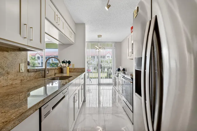 a kitchen with stainless steel appliances granite countertop a refrigerator and a sink