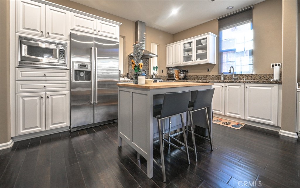 64 Scarlet Bloom Irvine, CA 92618 - Photo 17 of 22 a kitchen with kitchen island granite countertop wooden floors and white cabinets