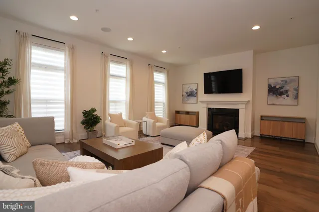 a large white dining hall with stainless steel appliances granite countertop a stove a sink a dining table with chairs and wooden floor