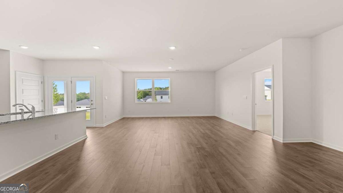 8576 Seabiscuit Road Lithonia, GA 30058 - Photo 8 of 22 an empty room with wooden floor and windows