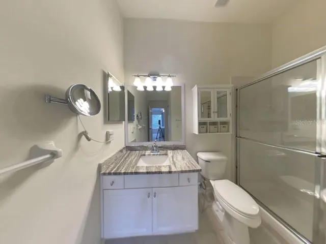 a bathroom with a granite countertop sink a toilet and shower