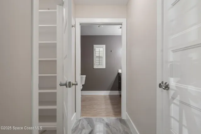 a view of an empty room with window and chandelier fan
